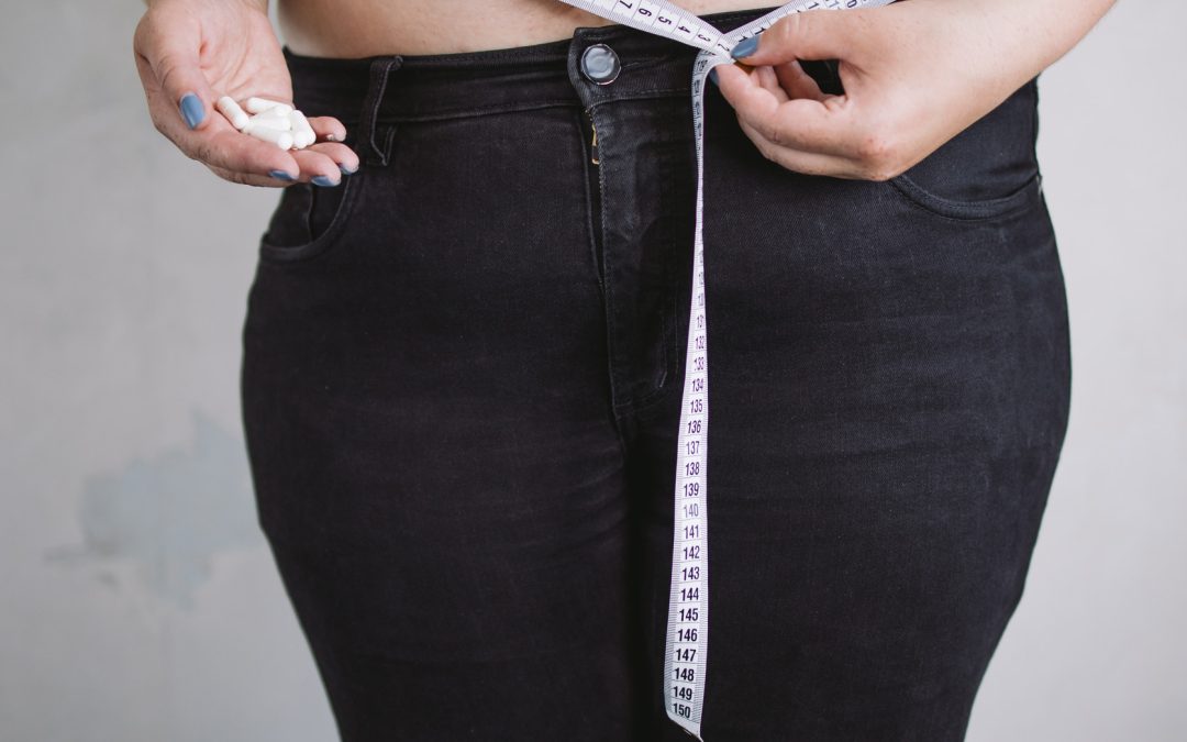 Obese woman with measuring tape and dietary supply