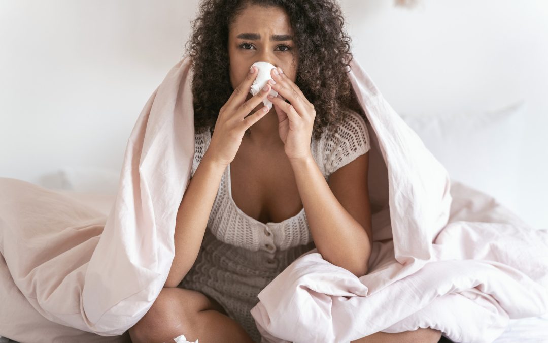 Sick curly haired girl sitting on the bed and looking at camera