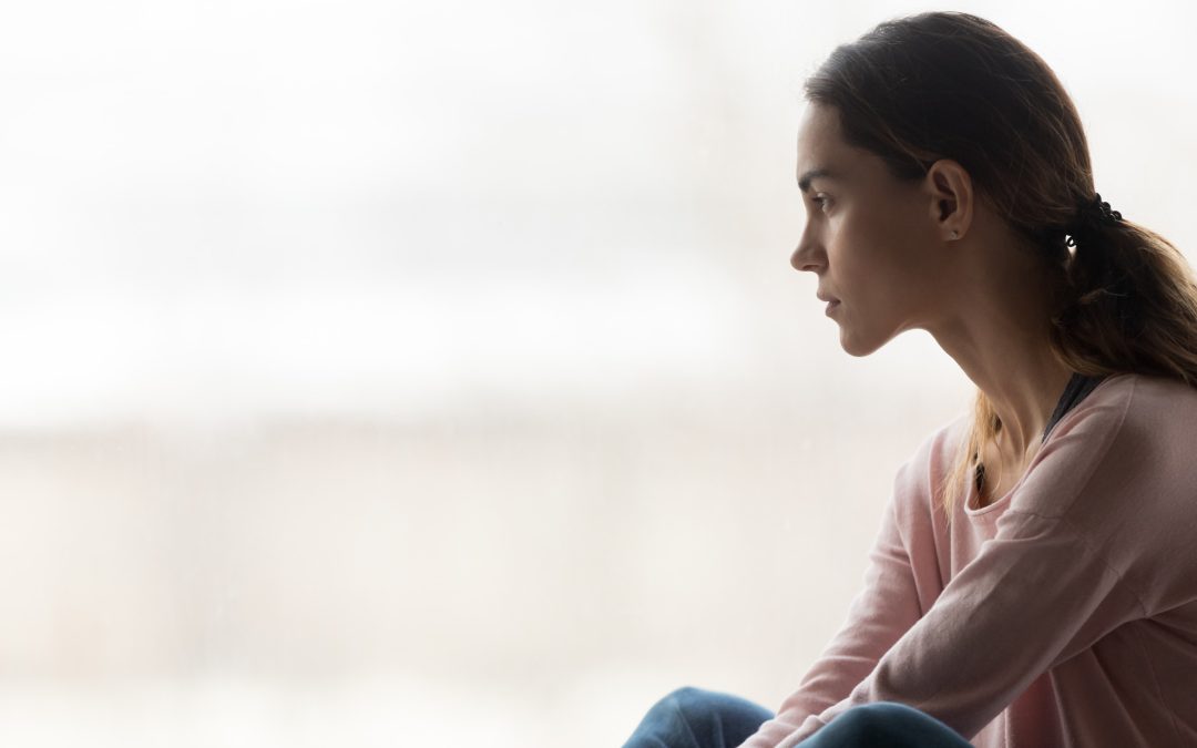 girl sitting alone looking through window