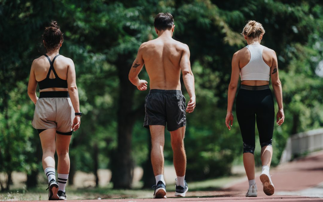 Three athletes walking on outdoor track, engaging in a fitness activity under sunny weather conditions